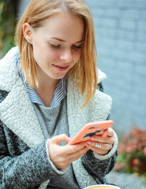 wanita tersenyum saat menggunakan teleponnya